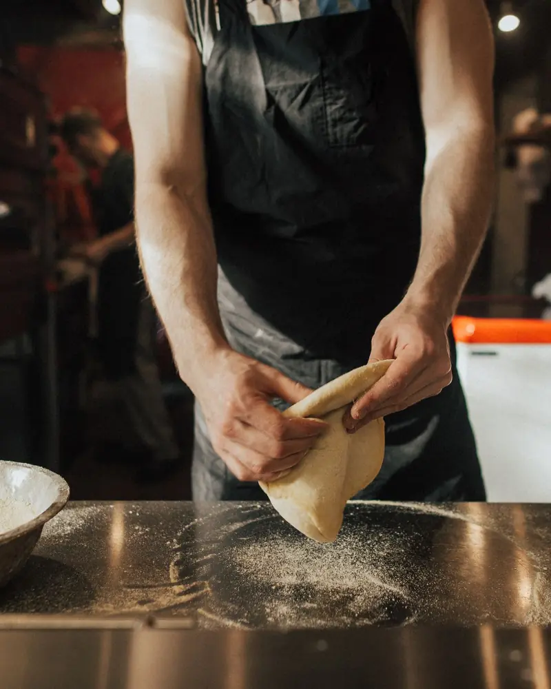 Pizzaiolo przygotowuje ciasto przy blacie