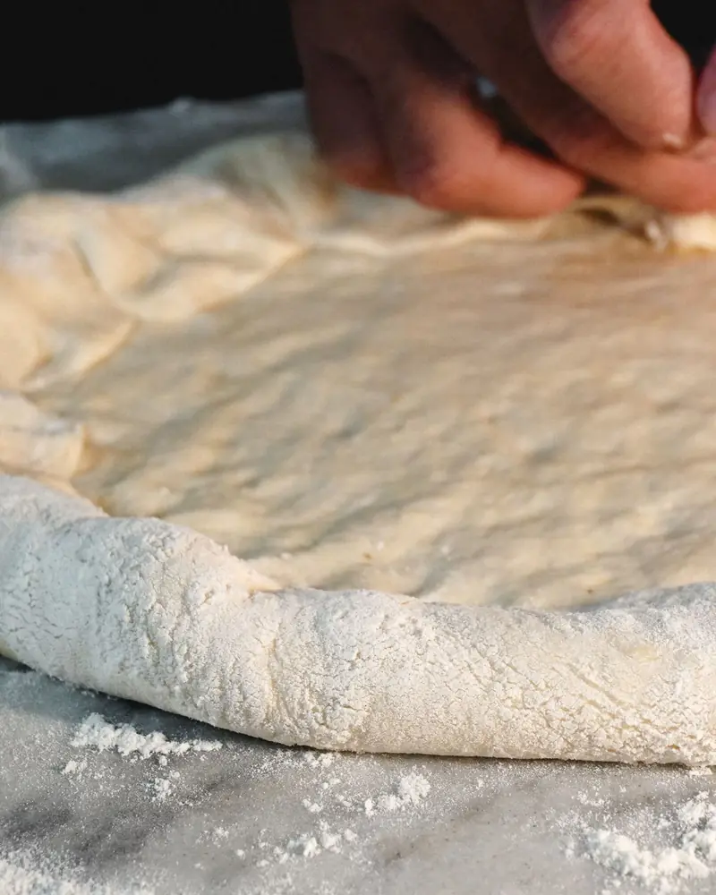 Dłonie formujące ciasto na pizzę