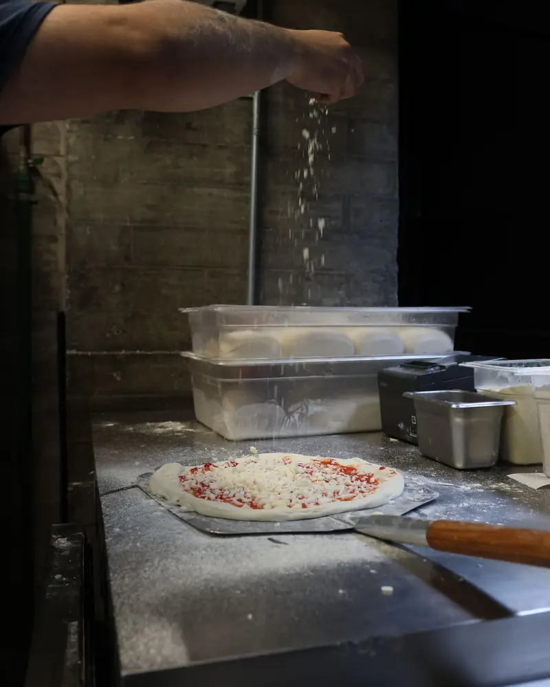 Posypywanie blatu mąką w kuchni pizzerii