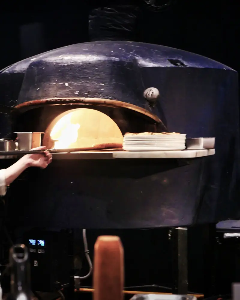 Pizzaiolo przy piecu w otwartej kuchni